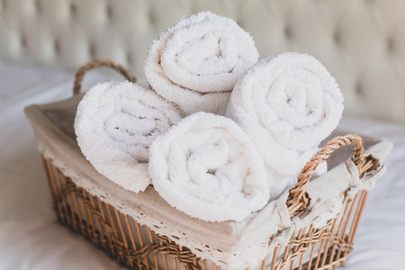 Four rolls of white terry towels lie in a wicker basket on a white background. Retro style.の写真素材