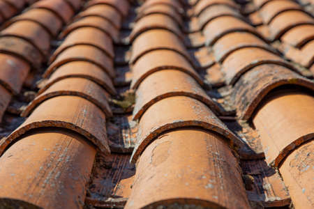 Fragment of an old tiled roof close-up. Tiled roof background.