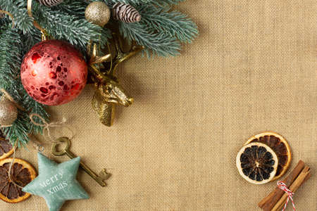 Beautiful Christmas decorations and a spruce branch are on the left side of the image on a burlap background. Background on a New Year's theme. Free space for text. Retro style.の写真素材