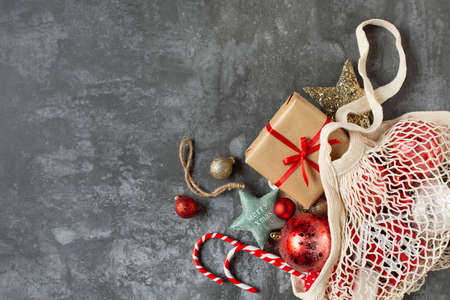 A gift and other beautiful Christmas decorations are in a bag on a gray background. Free space for...