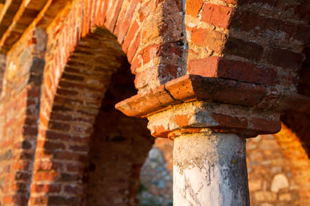 Fragment of the arch of an old building built of red brick.An old brick building illuminated by the sunset.の写真素材
