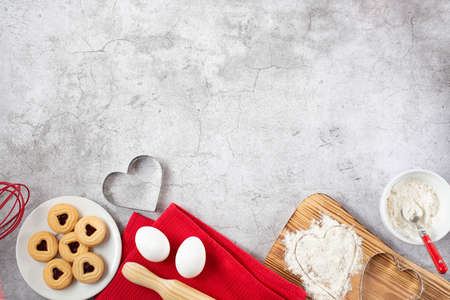 Background on the theme of Valentine's Day. Kitchen utensils and heart-shaped biscuit baking...