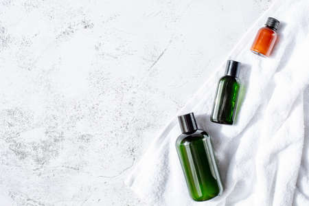 Three cosmetic jars of green and orange color are on a white bath towel on a gray background. The theme of natural cosmetics. Top view or flat lay. Copy space for text.の写真素材