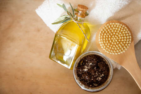 A jar of handmade coffee scrub, body brush with bottle of olive oil are on wooden background. Free...