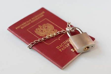 The passport of the Russian Federation chained in a chain with a padlock is located on a light...