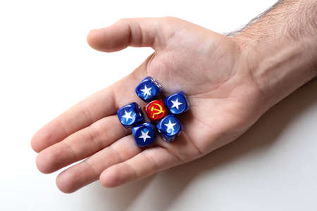 One dice with the symbol hammer and sickle surrounded by five blue cubes with the symbol usa star...