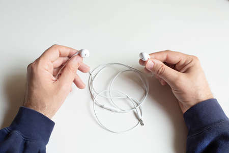 Men's hands are holding a wireless headphone on a gray background. View from the top point.の写真素材
