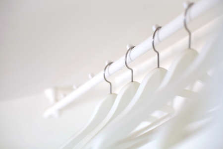 White wooden hangers hang on the crossbar on a white background.の写真素材