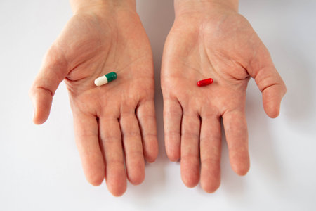 Two different tablets to choose lie on the female palms. The theme of medication treatment or the existence of choice.の写真素材