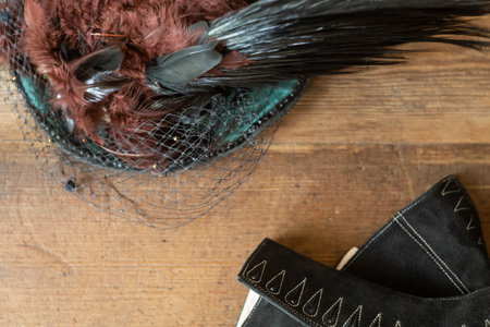 Women suede black shoes and a hat with feathers are on a wooden background. Retro or Victorian style. view from the top. copyspace.の写真素材
