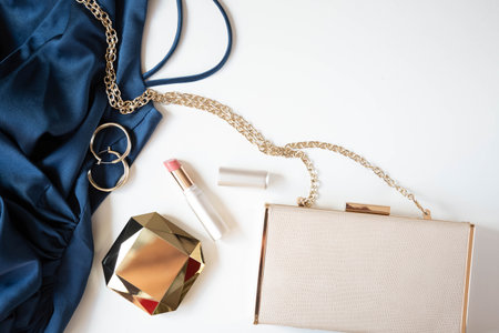 Women's gold-colored accessories cosmetics, handbag and cocktail dress in blue are on a light background. copyspace.の写真素材