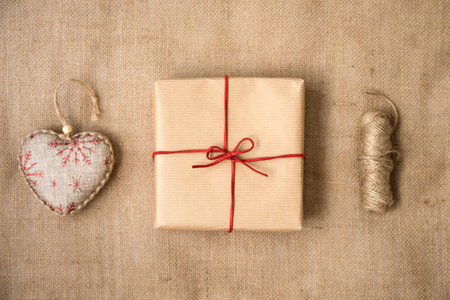 Wrapped in paper with a red ribbon, the gift, the Christmas heart and the coil of rope are on the backdrop of the sack. Preparation for Christmas. View from the top.の写真素材