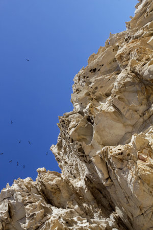 Part of a rock of bizarre shape against a blue sky with birds.Cabo San Lucas, Mexico. Vertical image.の写真素材