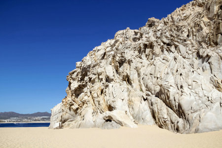 The rock lit by the bright sun is on the sandy shore of the Pacific Ocean.. Cabo San Lucas, Mexico.の写真素材