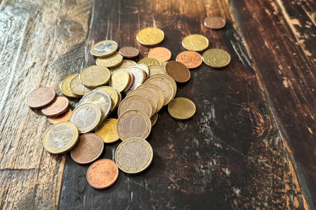 A pile of metal euro coins is on a wooden table. Metal coins scattered on the table.の写真素材