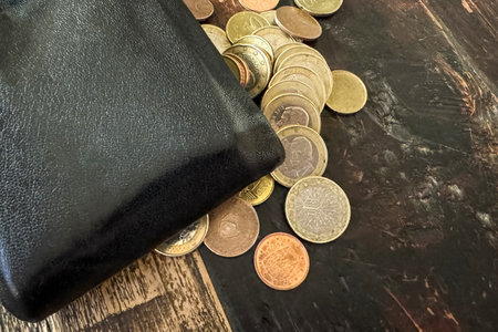The men's leather purse and the euro coins are on a wooden table.