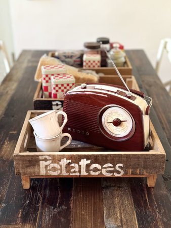 Radio in retro style and cups are in wooden kitchen boxes on a wooden table in the dining room. Vintage or English style.の写真素材