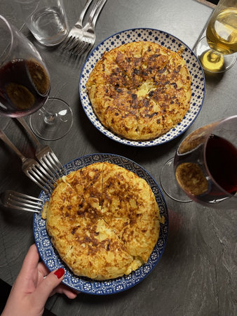 Served with plates with potato omelet and wine glasses. View from the top. Vertical image. Traditional and national Spanish omelet.の写真素材
