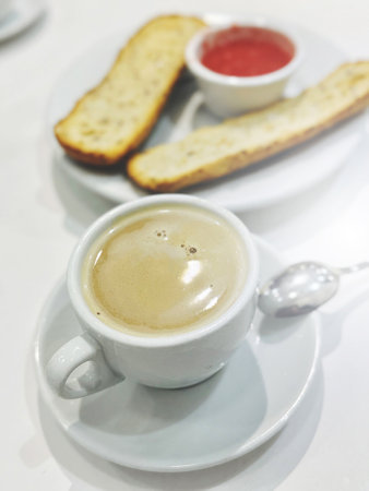 A white cup of espresso coffee and toasted bread with fresh tomato pasta for breakfast are on the table. Vertical image. Traditional Spanish breakfast.の写真素材