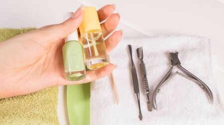 Manicure. A woman holds nail polishes and cuticle oil. Manicure tools. Home nail care, SPA, beauty. Long natural nails. Beauty salon.の写真素材
