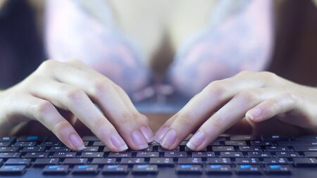 A woman in her underwear is typing on a keyboard.の写真素材