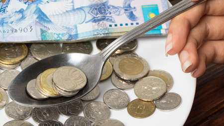 Keep the coins in the spoon. Tenge, the national currency of Kazakhstan. Concept. Budget, living...