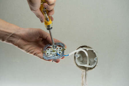 A man installs an electrical outlet in the wall. Installation wire into a plug. Close up of...