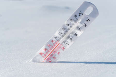 Thermometer in the snow. Climate, weather, forecast. Temperature outside. Thermometer in the snow shows temperatures below zero. Low temperatures in degrees Celsius and fahrenheit in snowy weatherの写真素材