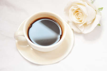 cup of coffee with white roses in the morningの写真素材