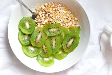a plate of delicious oatmeal with green kiwi in the morningの写真素材