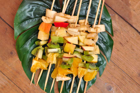 Fruit barbecue on leaf of monstera and wooden backgroundの写真素材