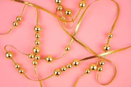 Golden beads on pink background copy spaceの写真素材