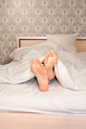 Womans feet under the blanket in the morningの写真素材