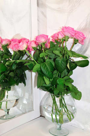Pink roses in glass vase near the mirrorの写真素材