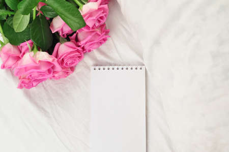 Bouquet of pink roses on the white linens on bedの写真素材