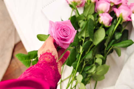 Bouquet of pink roses on the white linens on bedの写真素材