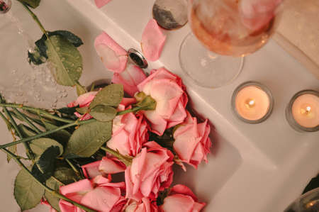 Glass of wine and bouquet of pink roses in sinkの写真素材