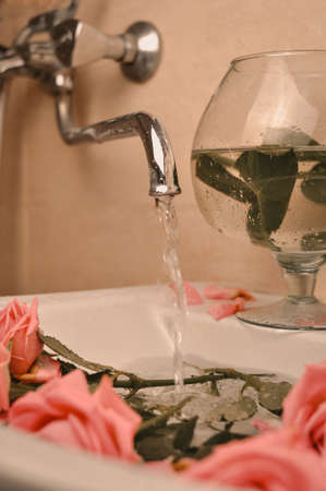 Glass of wine and bouquet of pink roses in sinkの写真素材