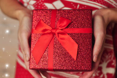Present red box with bow in hands giving giftsの写真素材