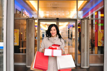 Young brunette woman with gifts and shopping bagsの写真素材