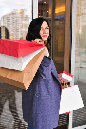 Young brunette woman with gifts and shopping bagsの写真素材