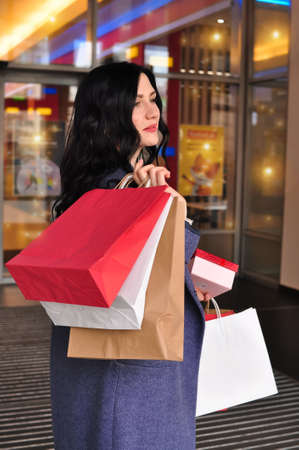 Young brunette woman with gifts and shopping bagsの写真素材