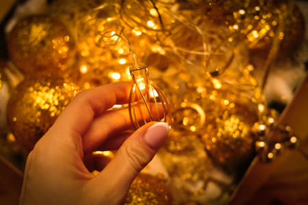 Womans hand holding Golden christmas decorations for tree and homeの写真素材