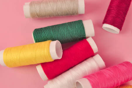 Multicolored threads for sewing on pink background . High quality photoの写真素材