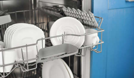 Dishwasher with white plates and cups on the kitchen . High quality photoの写真素材