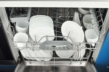 Dishwasher with white plates and cups on the kitchen . High quality photoの写真素材