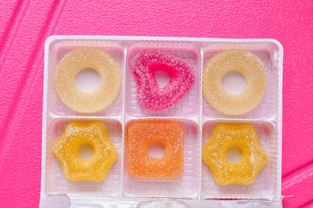 Sweet sugar marmalade different geometric forms on pink background . High quality photoの写真素材