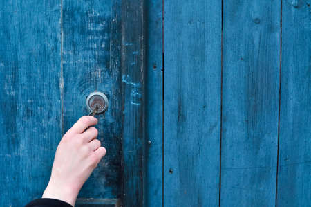 Close up of hand with key opening lock on the wooden door. High quality photoの写真素材
