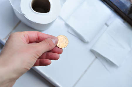 Roll of white toilet paper and golden Ukrainian hryvnia coin. Translation from Ukrainian :one hryvnia, Ukraine. High quality photoの写真素材
