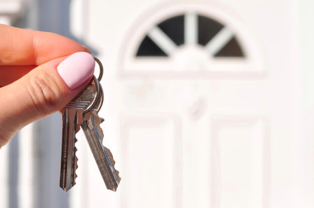 Womans hand with metal keys on blurred background with house. High quality photoの写真素材